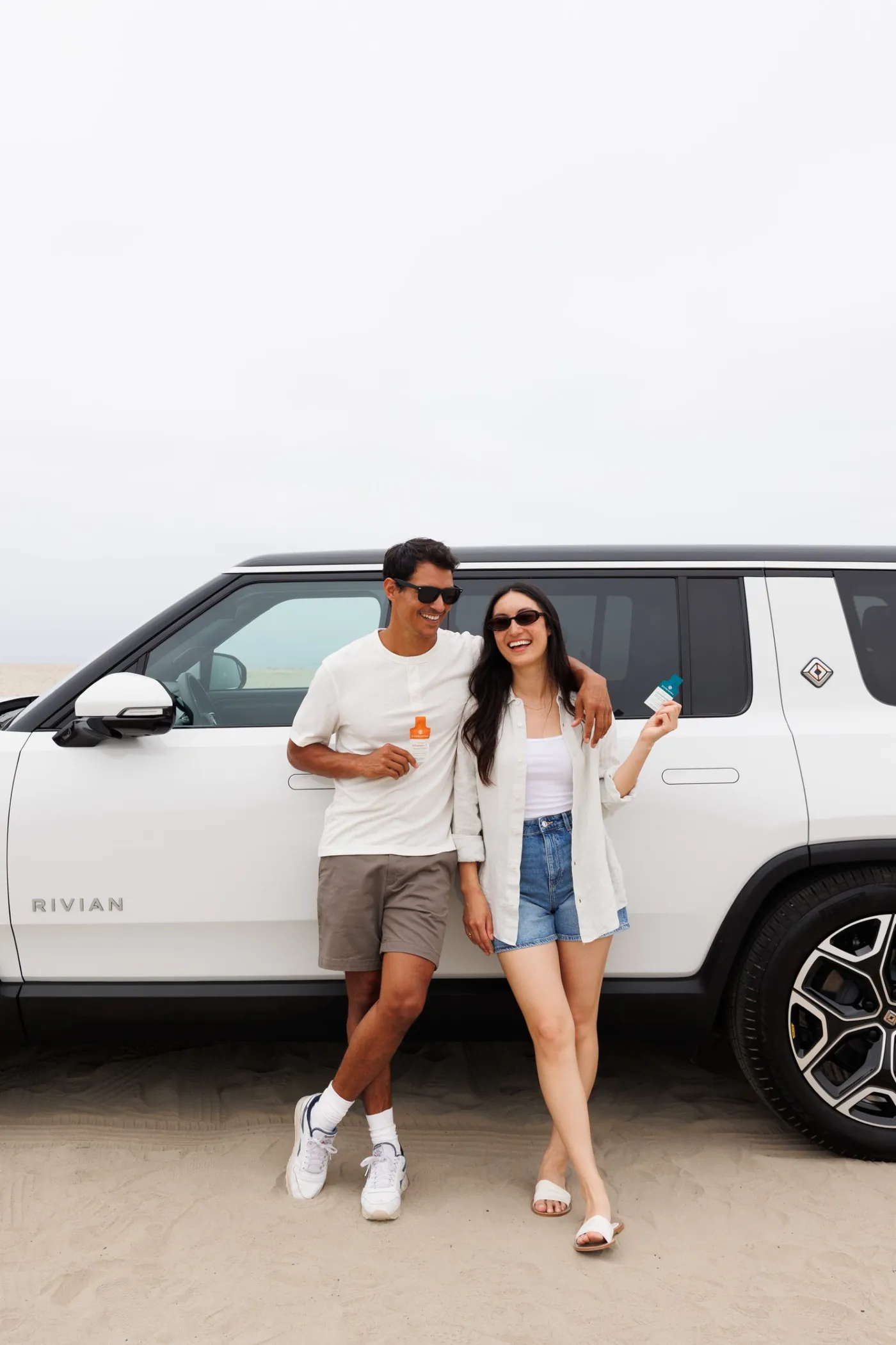 Couple leaning on the Rivian at the beach